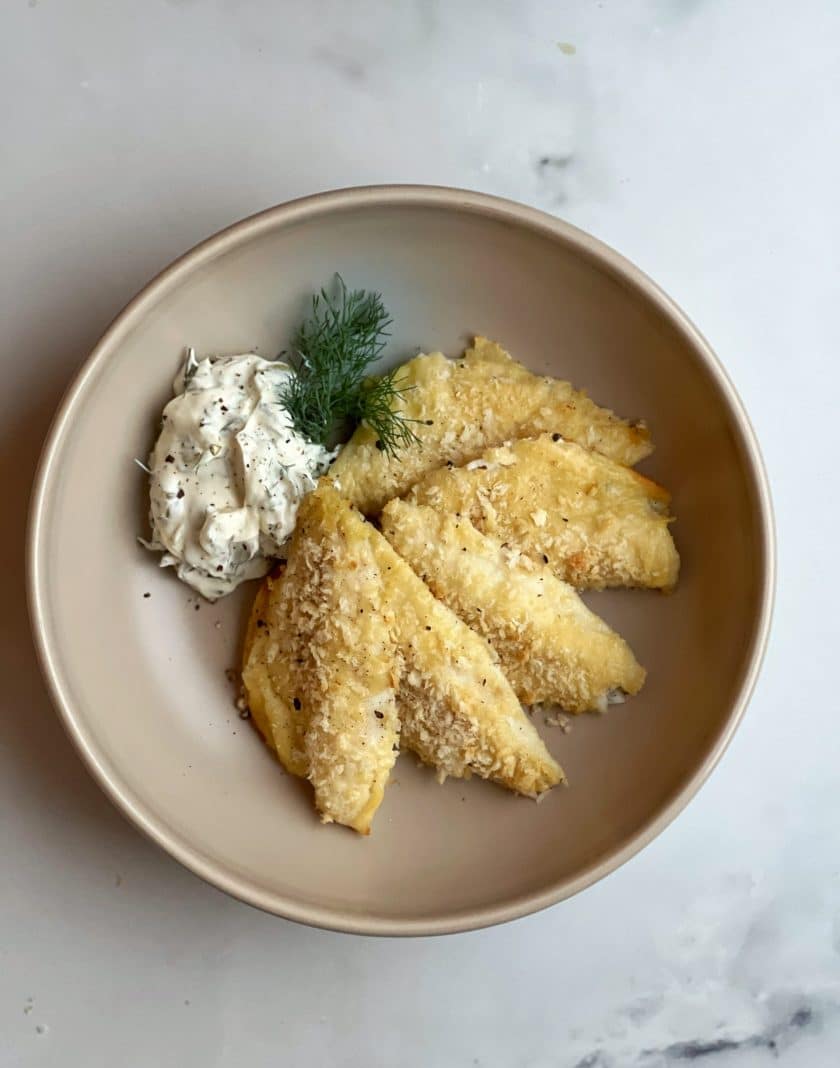Fischknusperli in Bierteig aus dem Ofen, serviert auf einem Teller, garniert mit Dill