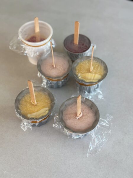 🔹 Pro Becher immer abwechselnd Heidelbeer-Joghurt, Erdbeer-Joghurt und Mango Lassi einfüllen. 🔹Nach dem Schichtvorgang Klarsichtfolie darüber spannend, einen kleinen Ritz machen und den Holzstängel hineindrücken. 🔹Mindestens 6–8 Stunden (am besten über Nacht) bei -18°C gefrieren. 🔹Entformen: Becher kurz in warmes Wasser tauchen, um Eis zu lösen.