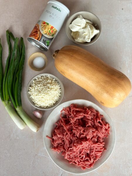 Zutaten 1 mittelgrosser Butternusskürbis 400 g gemischtes Hackfleisch 1 Bund Frühlingszwiebeln 1 Knoblauchzehe 2 EL Olivenöl von Nahrin 100 g Frischkäse 1 EL Pizza & Pasta Mix von Nahrin 100 g geriebener Käse z.B. Gruyer 1 TL Salz Pfeffer 2 EL Joghurt zum servieren