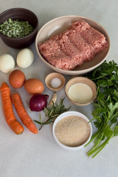 Zutaten: 4 Eier 2 Karotten 100 g Erbsen (frisch oder tiefgekühlt) 1 kleine Zwiebel, fein gewürfelt 1 Knoblauchzehe, gehackt 500 g Poulet-Hackfleisch 3 EL Paniermehl 2 EL Rahm 1 TL Rosmarin, frisch gehackt oder getrocknet Salz und Pfeffer nach Geschmack 1 EL Olivenöl