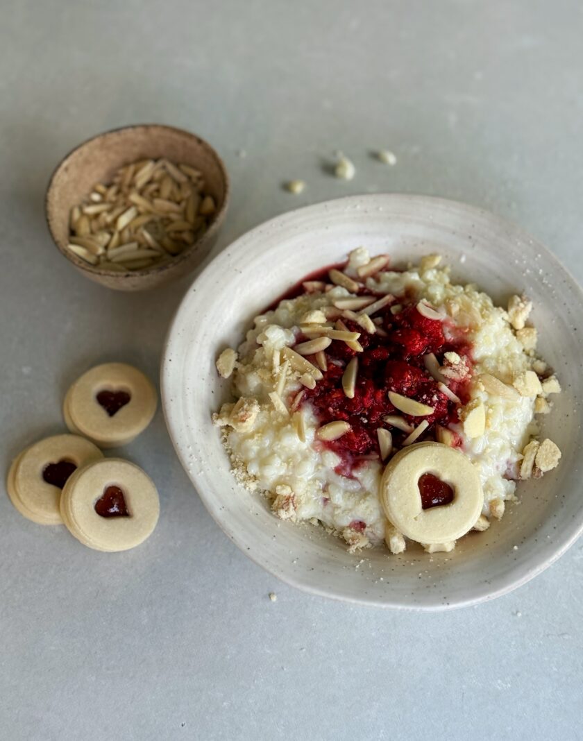 Die Milch in einem Topf langsam erhitzen, bis sie fast kocht. Den Reis hinzufügen, die Hitze reduzieren und den Milchreis bei schwacher Hitze unter häufigem Rühren etwa 25-30 Minuten köcheln lassen, bis der Reis weich ist und der Brei cremig wird. Dabei darauf achten, dass die Milch nicht überkocht oder anbrennt. Himbeeren mit Ahornsirup kurz aufkochen und kurz köcheln, ca. 2 min. Warmer Milchreis auf zwei Schüsseln verteilen und kleine Mulden in der Mitte eindrücken. Himbeeren direkt heiss in die Mulde leeren, Spitzbuben Guetzli zerbröckeln und darüberstreuen und mit Mandeln servieren.