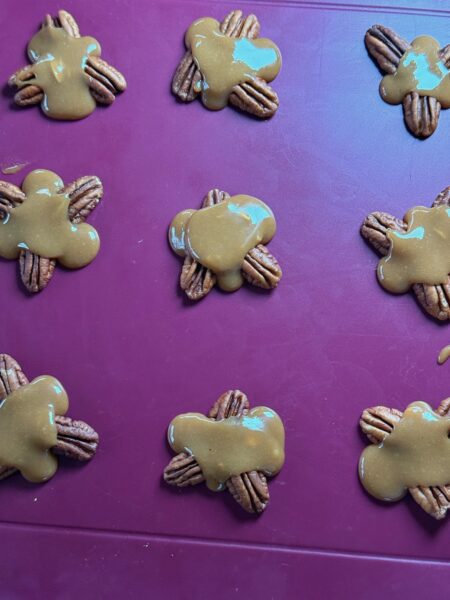 Carameltäfeli in einer Pfanne bei mittlerer Hitze mit Rahm schmelzen, bis eine glatte Karamellsauce entsteht. Backpapier auf einem Blech auslegen. Jeweils 3 Pekannüsse pro Turtle zu kleinen "Schildkrötenpanzern" auf dem Backpapier platzieren (drei Nüsse bilden ein kleines Dreieck).