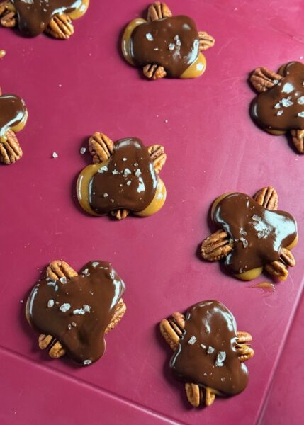 Mit einem Teelöffel Karamell vorsichtig über jede Nussgruppe geben, sodass die Nüsse zusammenhalten. Die Schokolade im Wasserbad schmelzen und jede "Turtle" grosszügig damit überziehen. Die Schokolade mit einem Löffel verteilen. Salz darauf verteilen. Turtles ca. 20-30 Min in den Tiefkühler stellen und servieren.