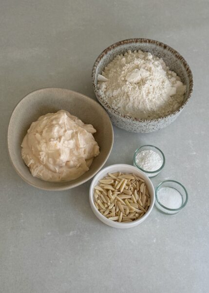 250 g Mehl z.B. Weissmehl 2 TL Backpulver 250 g Skyr Orange oder Natur 1 TL Salz 1 EL Wasser 2 EL Hagelzucker, Mandelnstifte (Optional) 4 Rosinen (Optional)